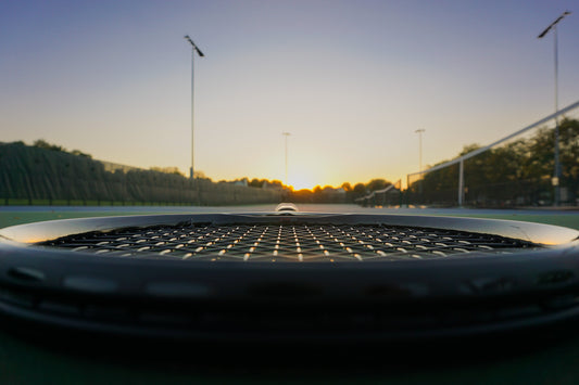 Sunset image of a tennis racket string bed at night on a tennis court